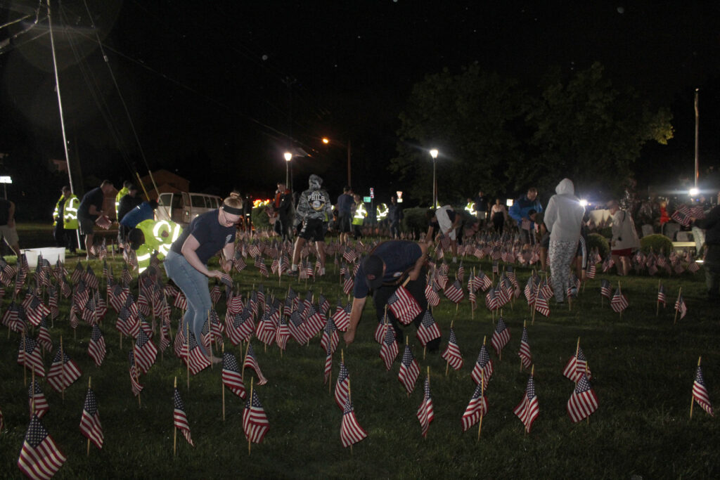 Members of the community place American flags at Pennsauken's 9/11 Memorial.